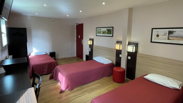 A hotel room with two beds, a desk, a TV, and two bedside lamps. - Brit Hotel Saint-Quentin (Fayet)