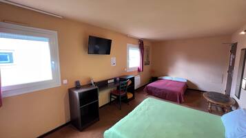 Habitación de hotel con dos camas, un escritorio con silla, televisor montado en la pared y ventana con cortinas.