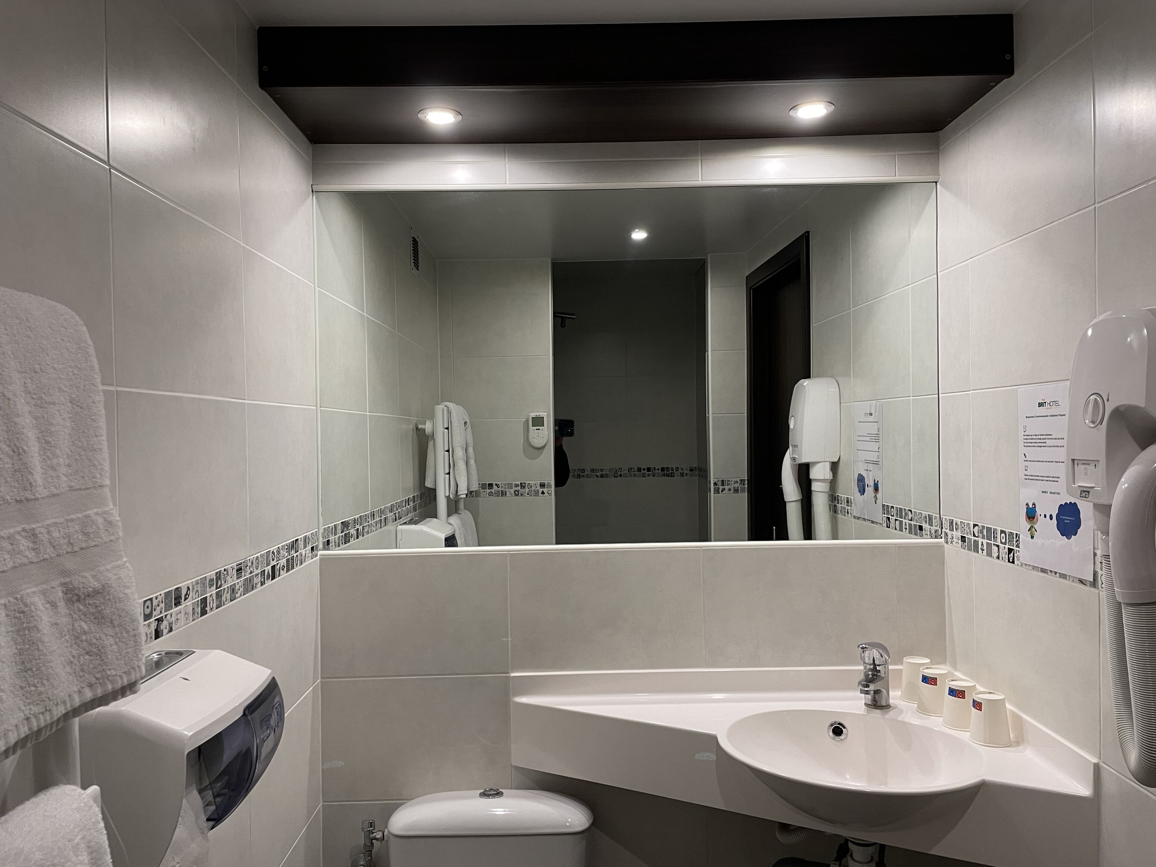 Een moderne badkamer met een grote spiegel, een wastafel en een toilet.