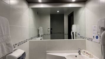 Een moderne badkamer met een grote spiegel, een wastafel en een toilet.
