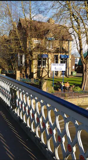 A hotel with a signboard, a fenced pathway, and leafless trees. - River Hotel (Oxford)