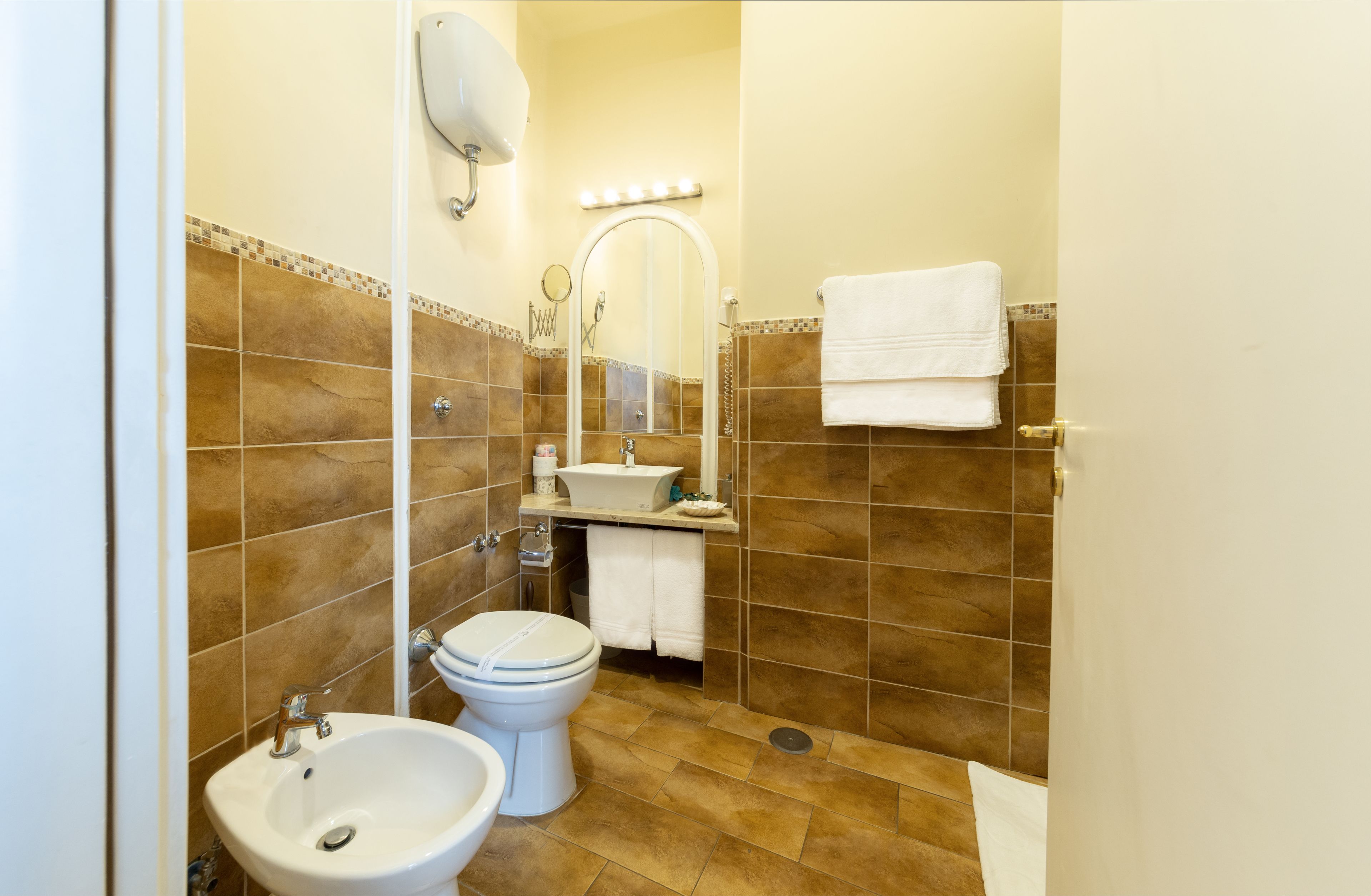 A bathroom with a sink, toilet, and mirror.