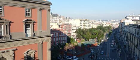 Une vue de rue avec des bâtiments, un ciel dégagé et une vue lointaine sur un paysage urbain.