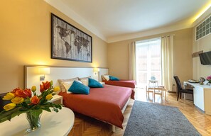 Habitación de hotel con dos camas, un escritorio, una silla, un televisor y una ventana con cortinas.