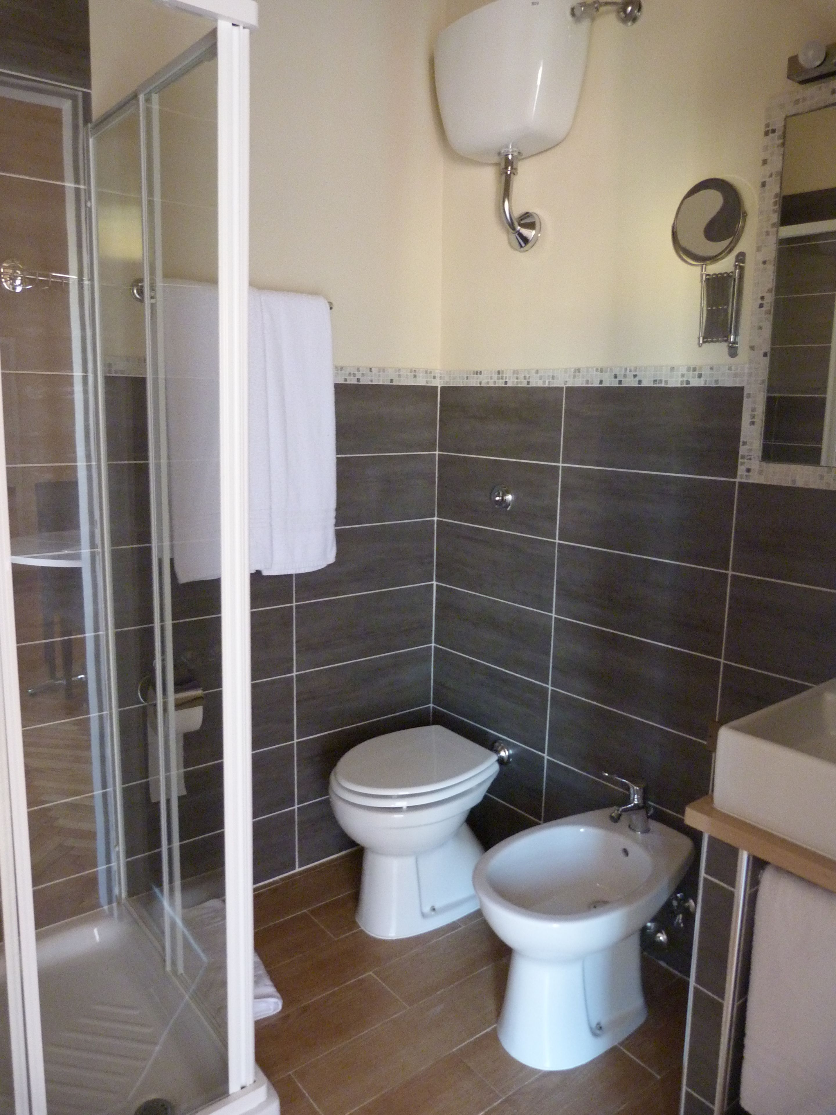 A bathroom with a shower, two toilets, and a bidet.