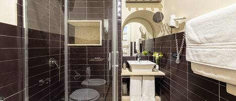 A modern bathroom with a glass-enclosed shower, two sinks, and a vanity area.
