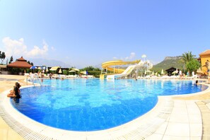 Una piscina al aire libre, sombrillas, sillones reclinables de piscina