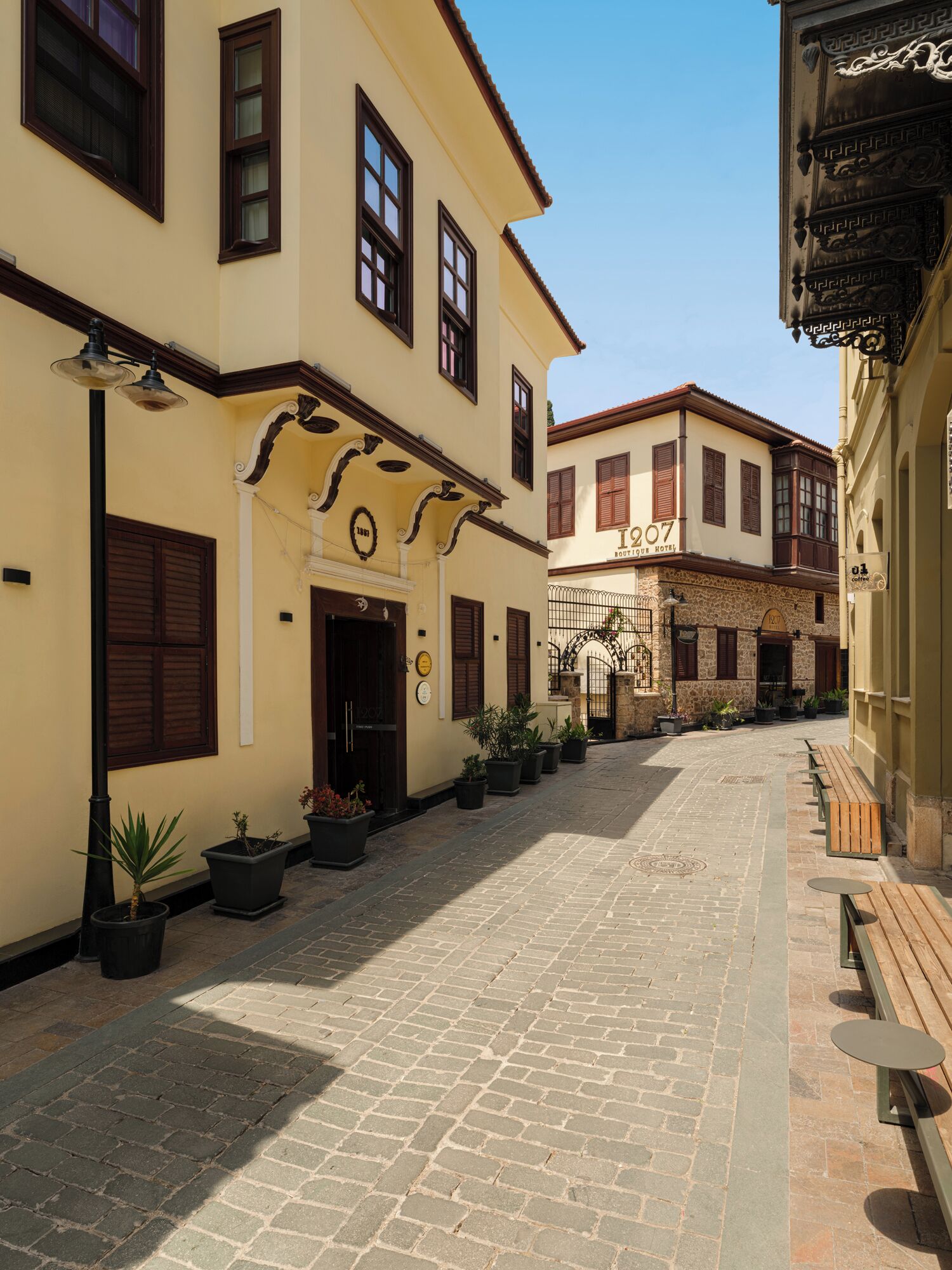 A cobblestone street lined with buildings featuring traditional architecture, including a hotel with a sign reading "Hotel 207."