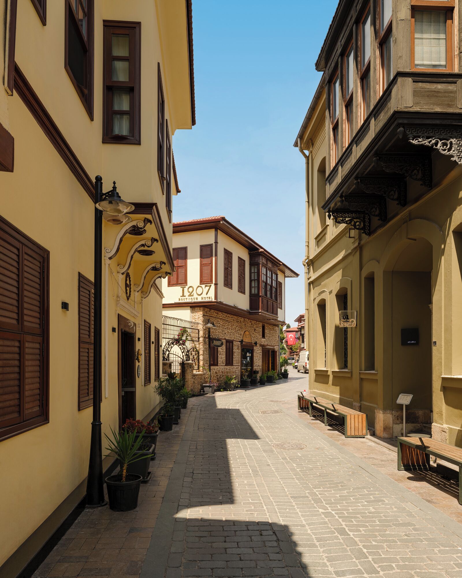 Una estrecha calle adoquinada flanqueada por edificios históricos, incluyendo un hotel boutique con fachada de piedra y contraventanas de madera.