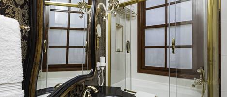 A luxurious bathroom with a large mirror, a black sink, and a glass-enclosed shower.