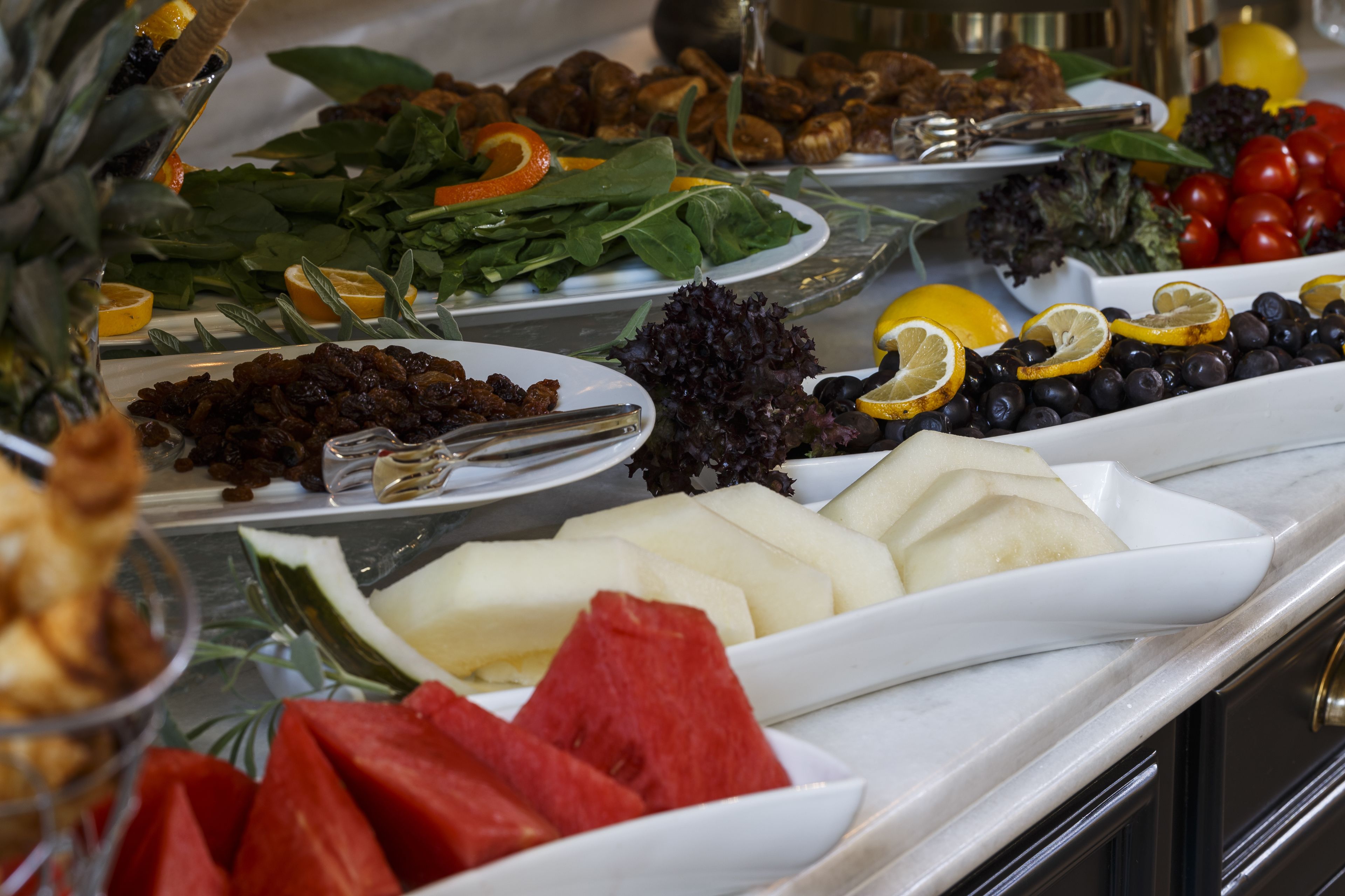 A buffet with various food items including fruits, vegetables, and cheeses.