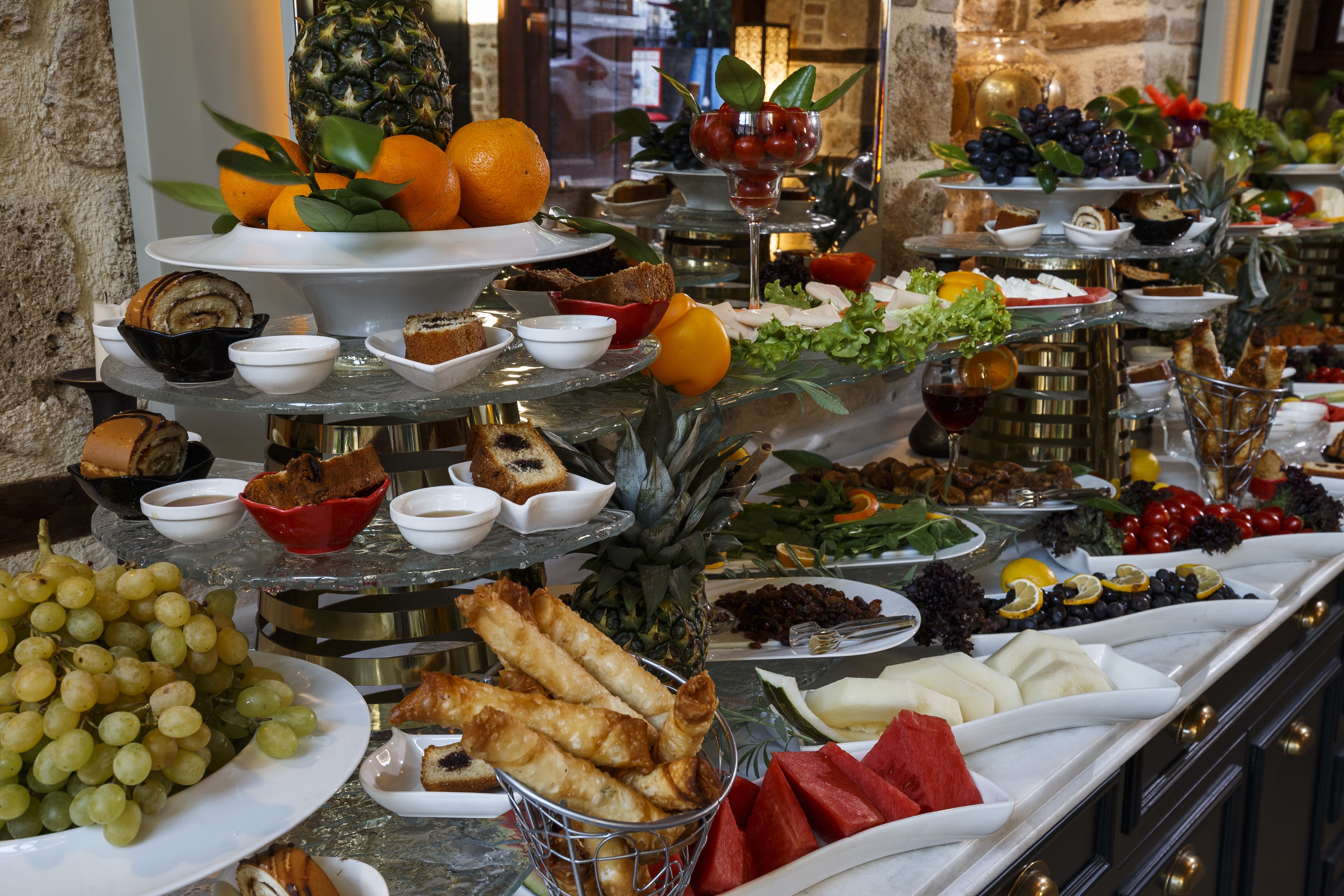 A buffet with various food items including fruits, cheeses, and bread.