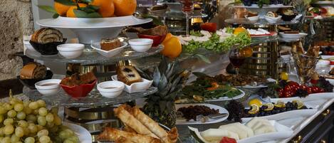 A buffet with various food items including fruits, cheeses, and bread.