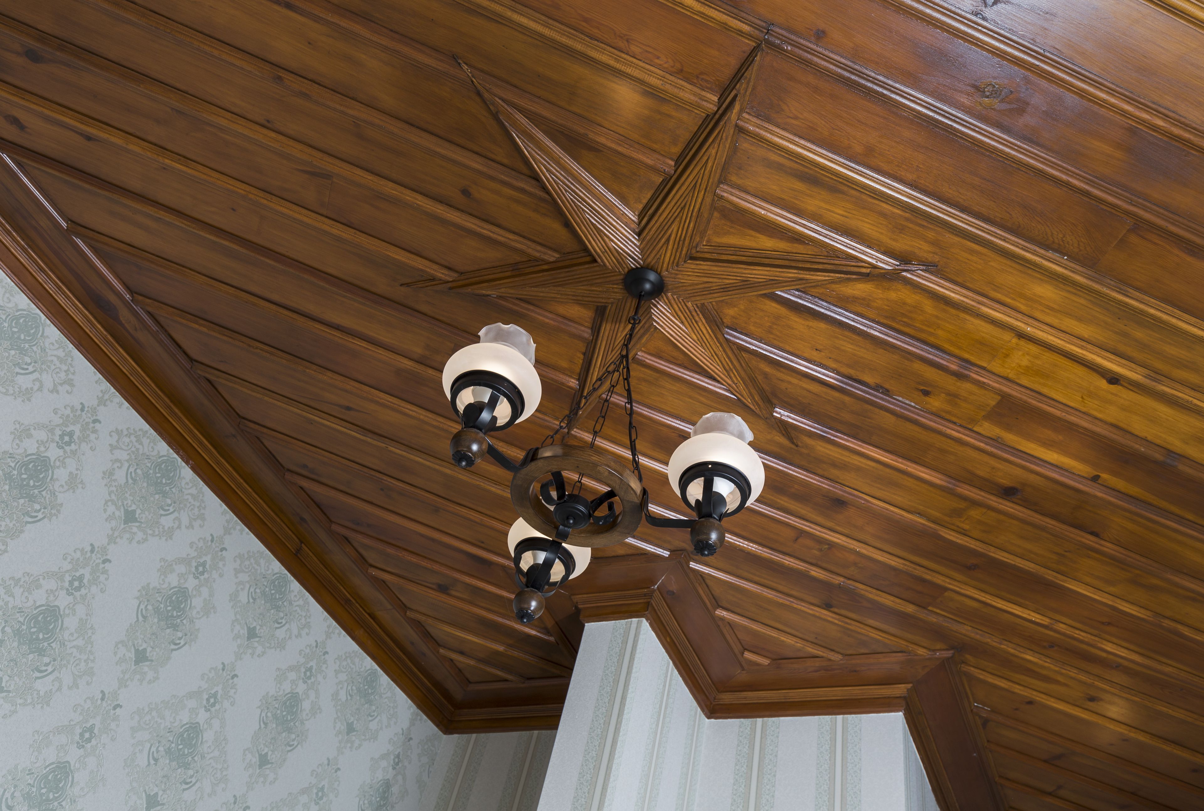 A wooden ceiling with a star-shaped chandelier.