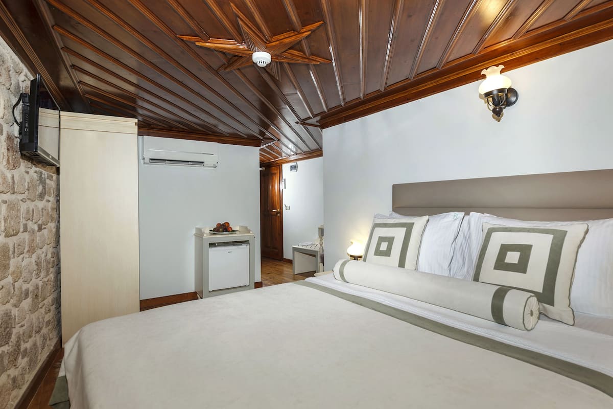 Een slaapkamer met een bed, nachtkastje, dressoir en plafondventilator.