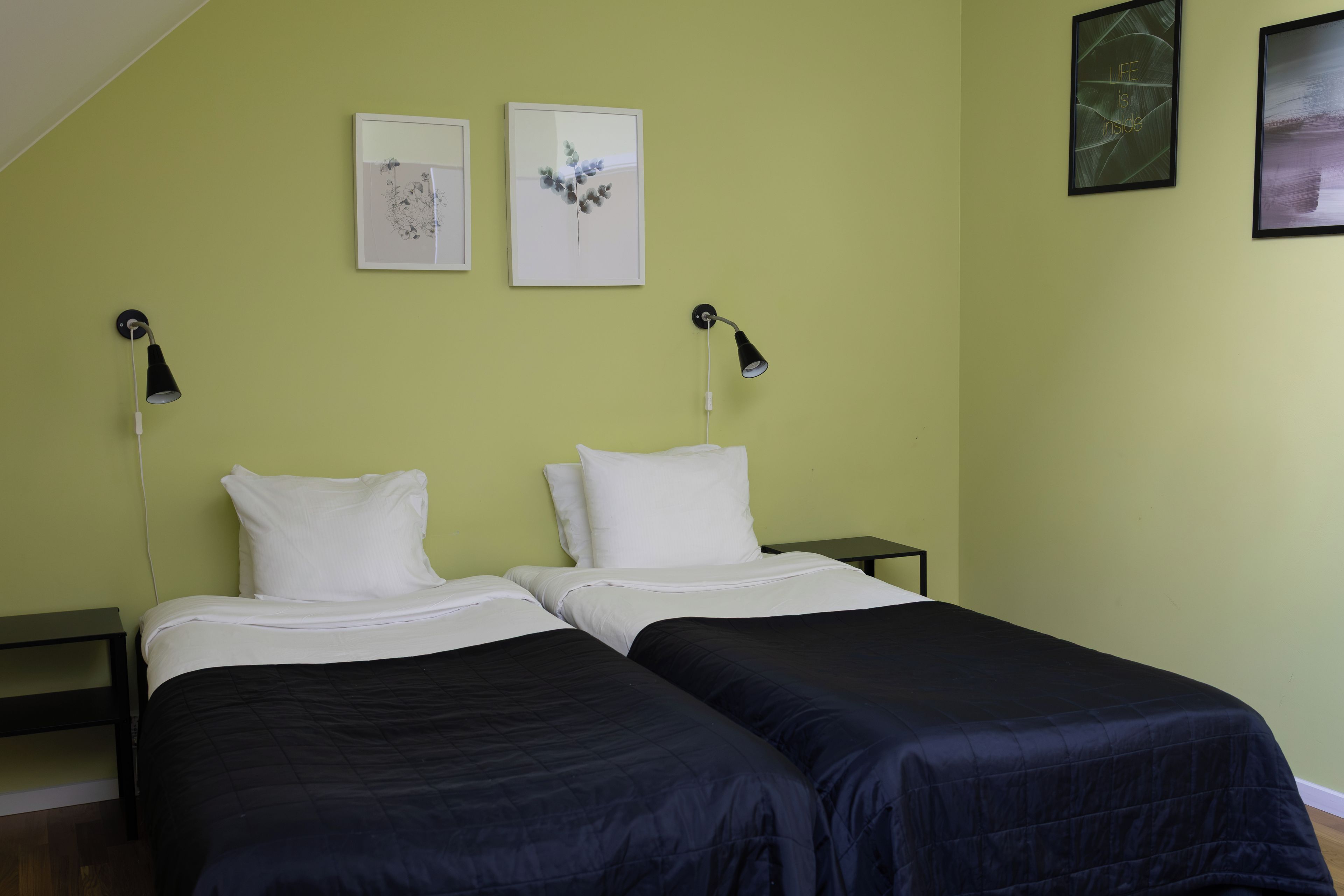Een kamer met twee bedden, een klein tafeltje en twee wandlampen.