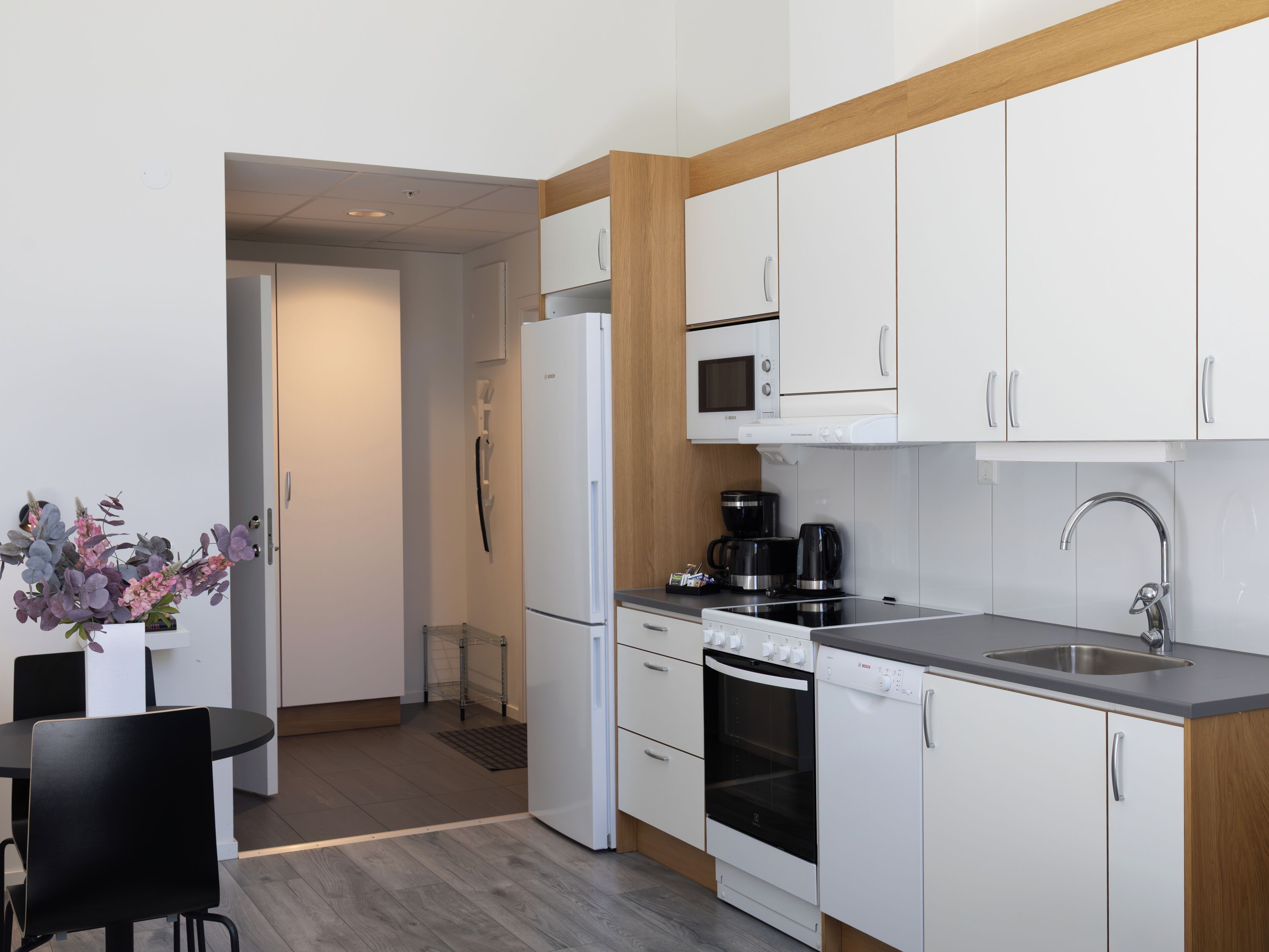 A modern kitchen with white cabinets, a microwave, a coffee maker, and a dishwasher.
