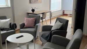 Un salon moderne avec des canapés gris, une table basse blanche et un tableau accroché au mur.