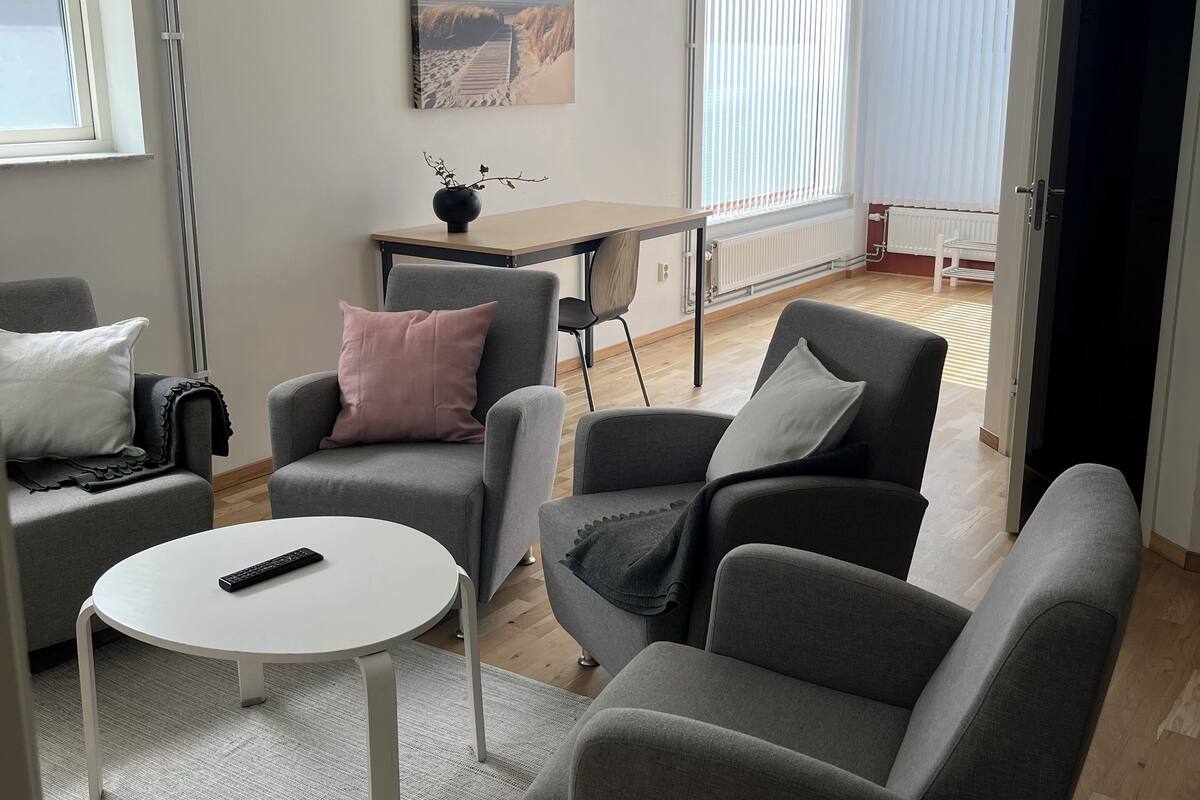 Ein modernes Wohnzimmer mit grauen Sofas, einem weißen Couchtisch und einem Gemälde an der Wand.