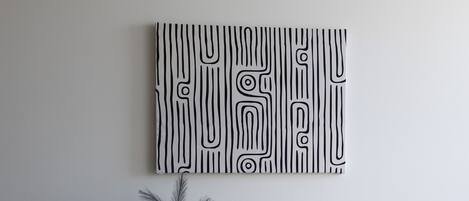 A minimalist room with a wooden desk, a black chair, and a wall-mounted abstract art piece.
