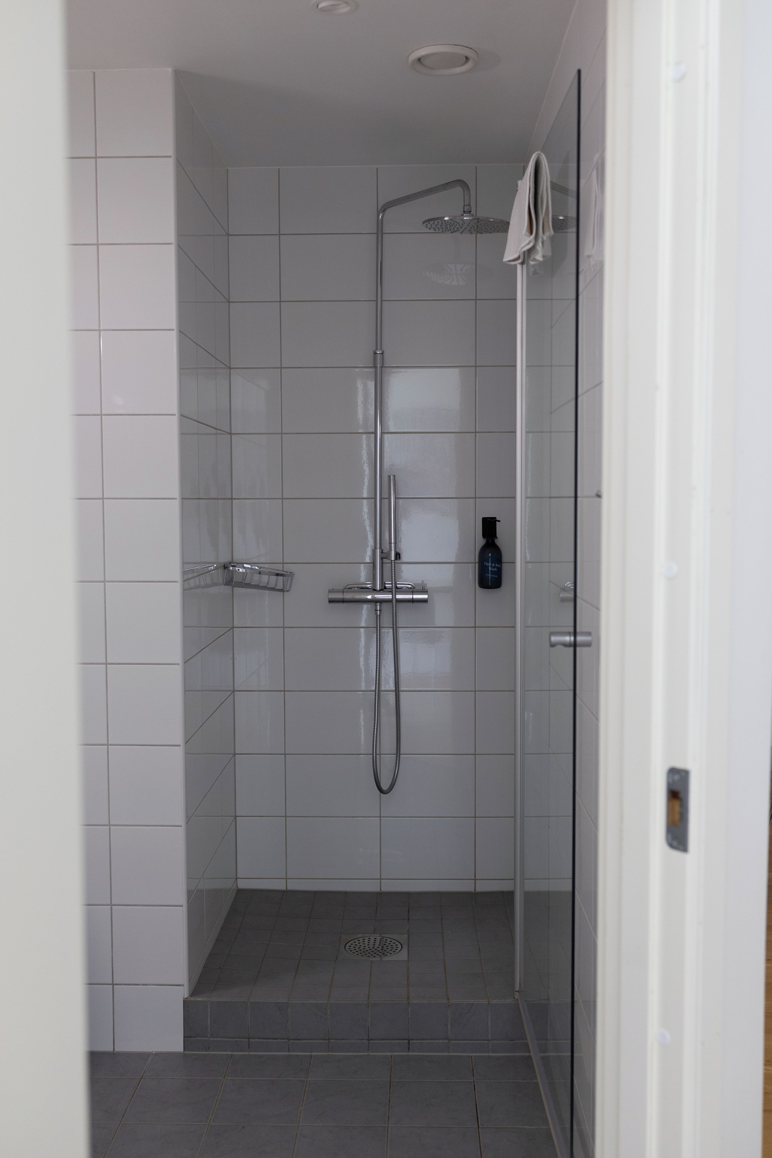 Ducha moderna con cabezal de ducha de mano y grifo empotrado.