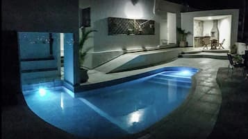 Una piscina al aire libre, sillones reclinables de piscina