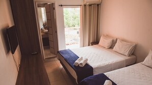 A hotel room with two beds, a TV mounted on the wall, and a bathroom visible through an open door. - Pousada Xerxes (Arraial do Cabo)