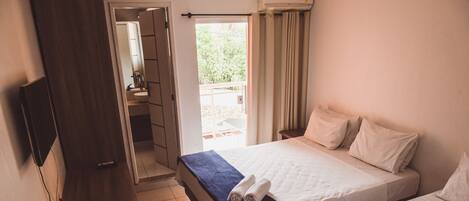 A hotel room with two beds, a TV mounted on the wall, and a bathroom visible through an open door.