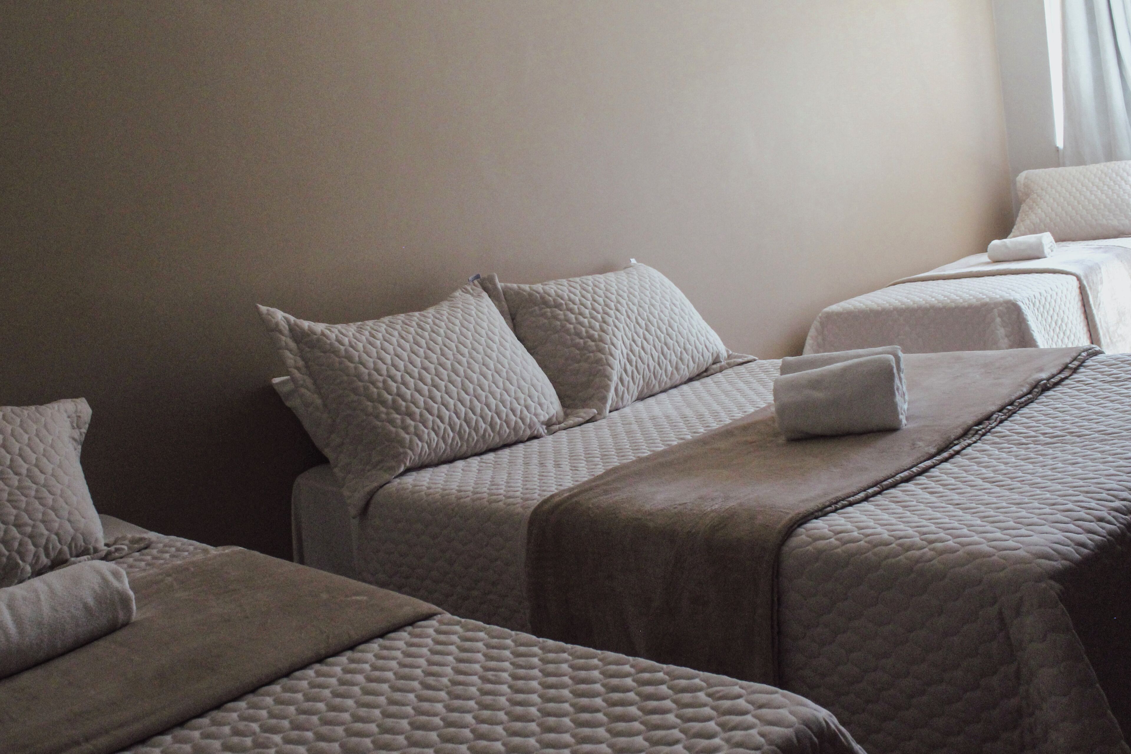 Ein Hotelzimmer mit zwei Betten, jeweils mit gesteppter Bettdecke und Kissen.
