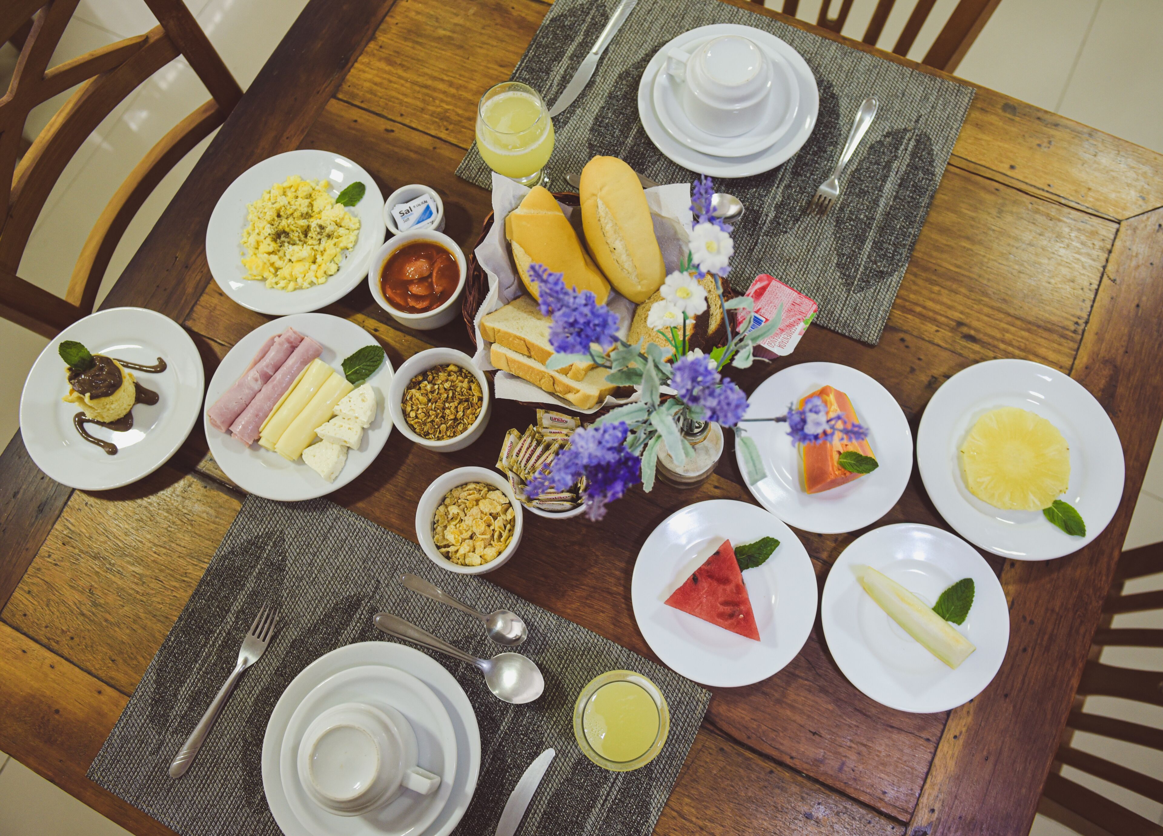 A dining table set with plates of food, utensils, and a vase of flowers.