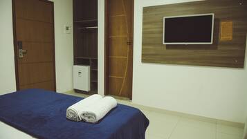 Quarto com cama, televisão na parede e guarda-roupa.