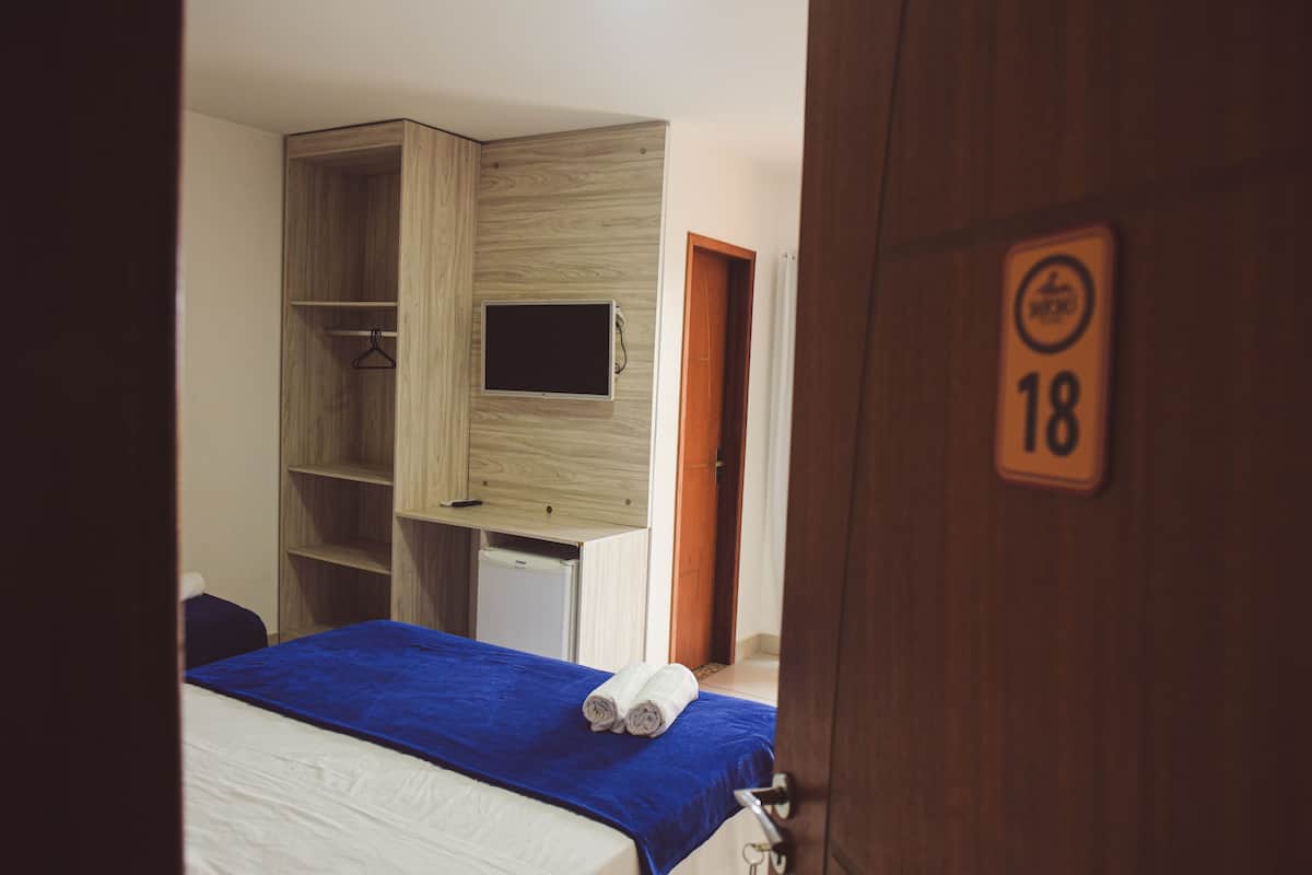 Ein Schlafzimmer mit einem Bett, einem an der Wand montierten Fernseher, einem Kleiderschrank und einer Tür mit einer Nummer.