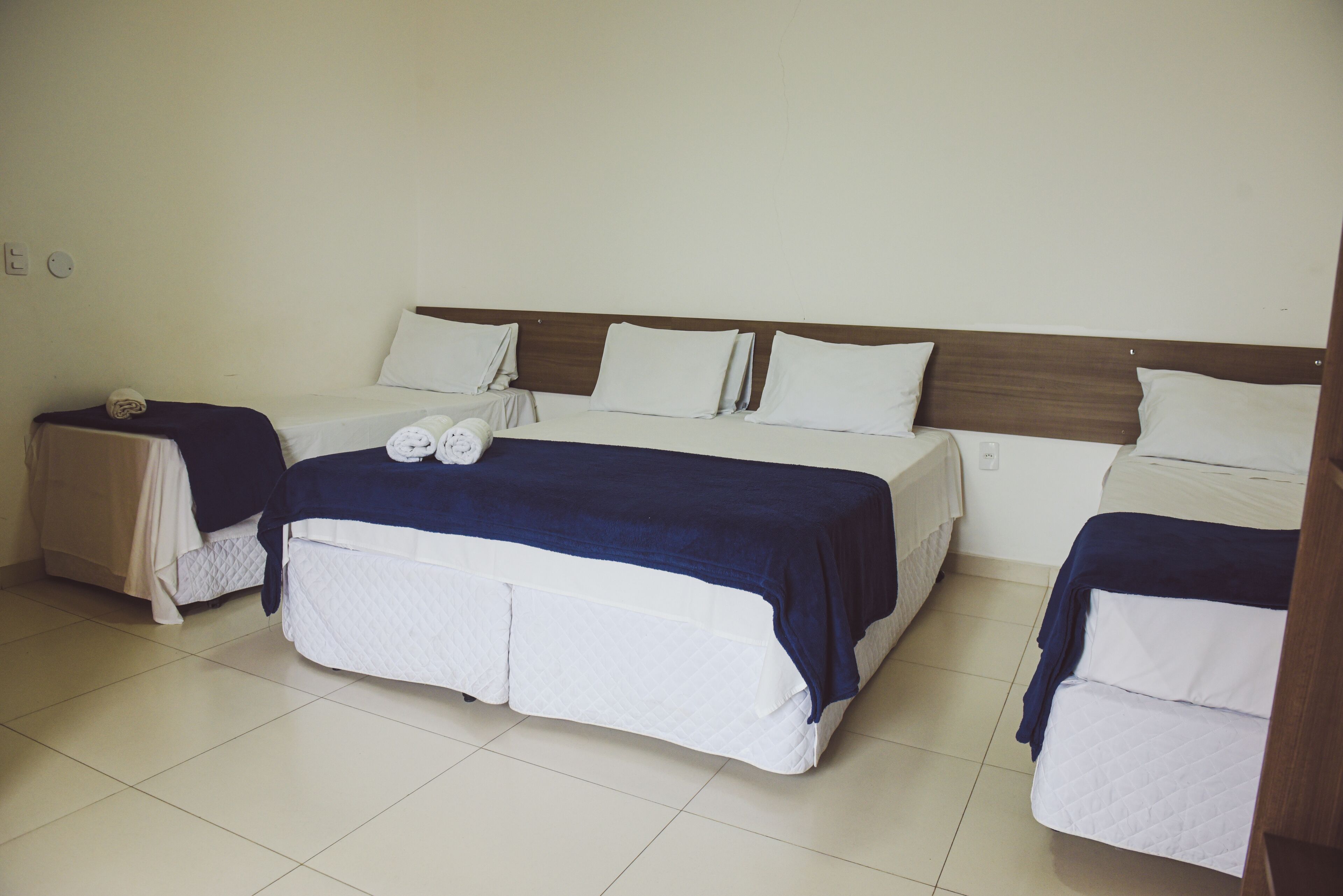A hotel room with two beds, a wooden headboard, and a tiled floor.