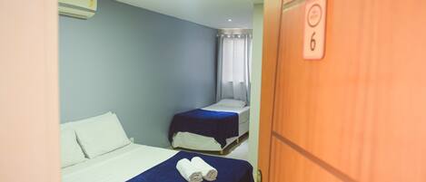 A room with two beds, a ceiling fan, and a door with a number.
