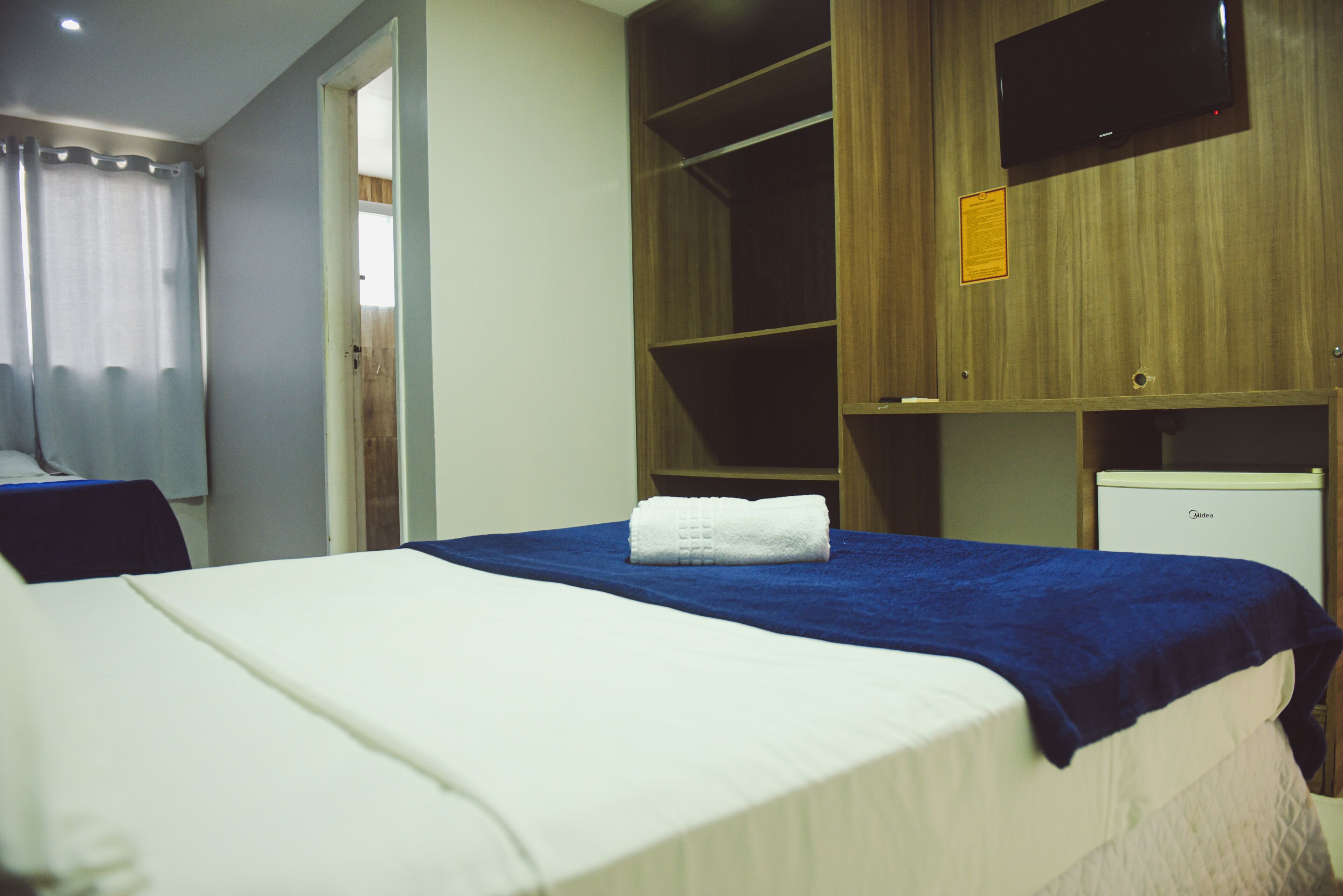 Une chambre d’hôtel équipée d’un lit, d’une armoire, d’une télévision et d’un bureau.