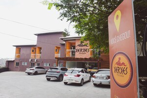 Un edificio con un letrero que dice "Xerxes Pousada" y un estacionamiento con varios coches.