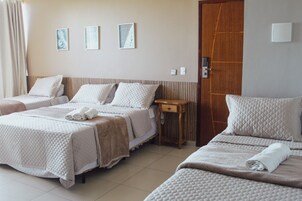 Una habitación de hotel con dos camas, una puerta de madera y tres cuadros en la pared.