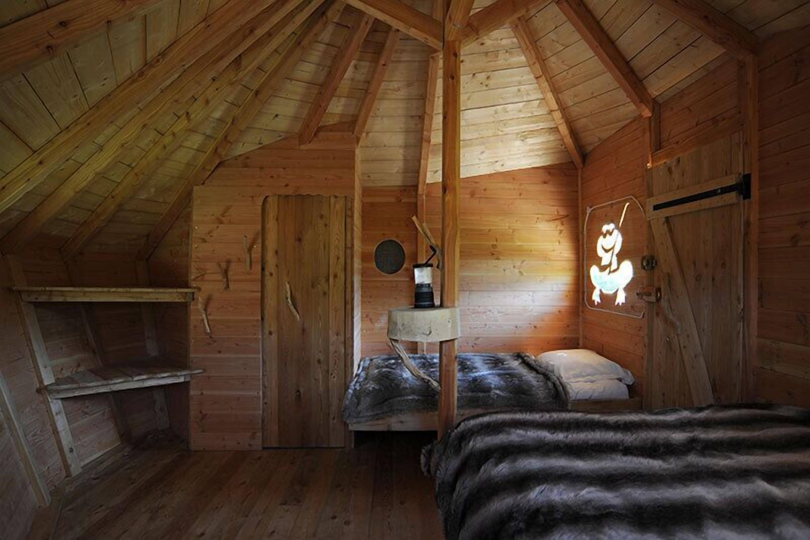 Uma cabana de madeira aconchegante com um quarto no mezanino, uma pequena escrivaninha e um aplique de parede.