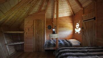 Uma cabana de madeira aconchegante com um quarto no mezanino, uma pequena escrivaninha e um aplique de parede.