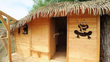 A wooden cabin with a thatched roof, a door, and a window.