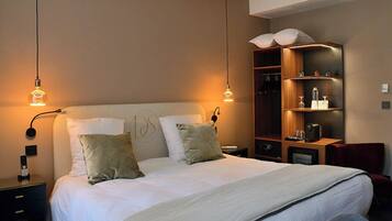 Habitación de hotel ordenada con una cama grande, mesitas de noche, un armario y lámparas colgantes.