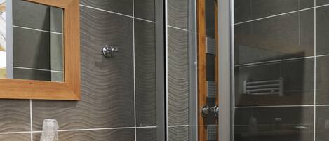 A modern bathroom with a glass shower enclosure, a wooden vanity with a sink, and a mirror above it.