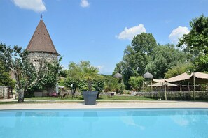 A swimming pool with a stone tower and trees in the background.