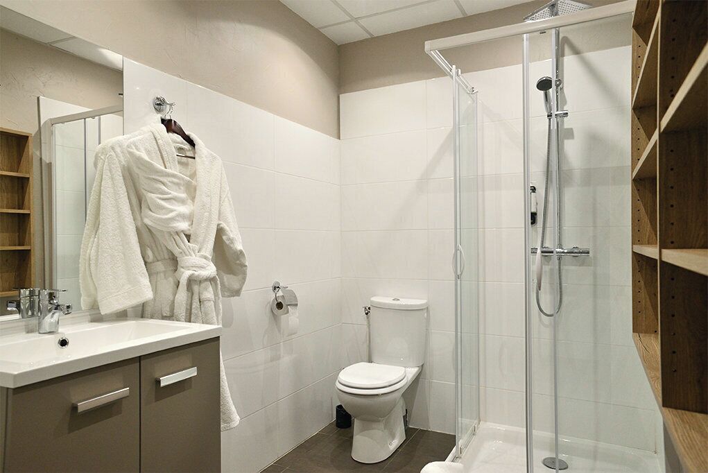 Une salle de bain moderne avec une douche à parois de verre, des toilettes blanches et un meuble-lavabo avec un miroir et un évier.