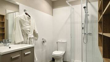 Une salle de bain moderne avec une douche à parois de verre, des toilettes blanches et un meuble-lavabo avec un miroir et un évier.