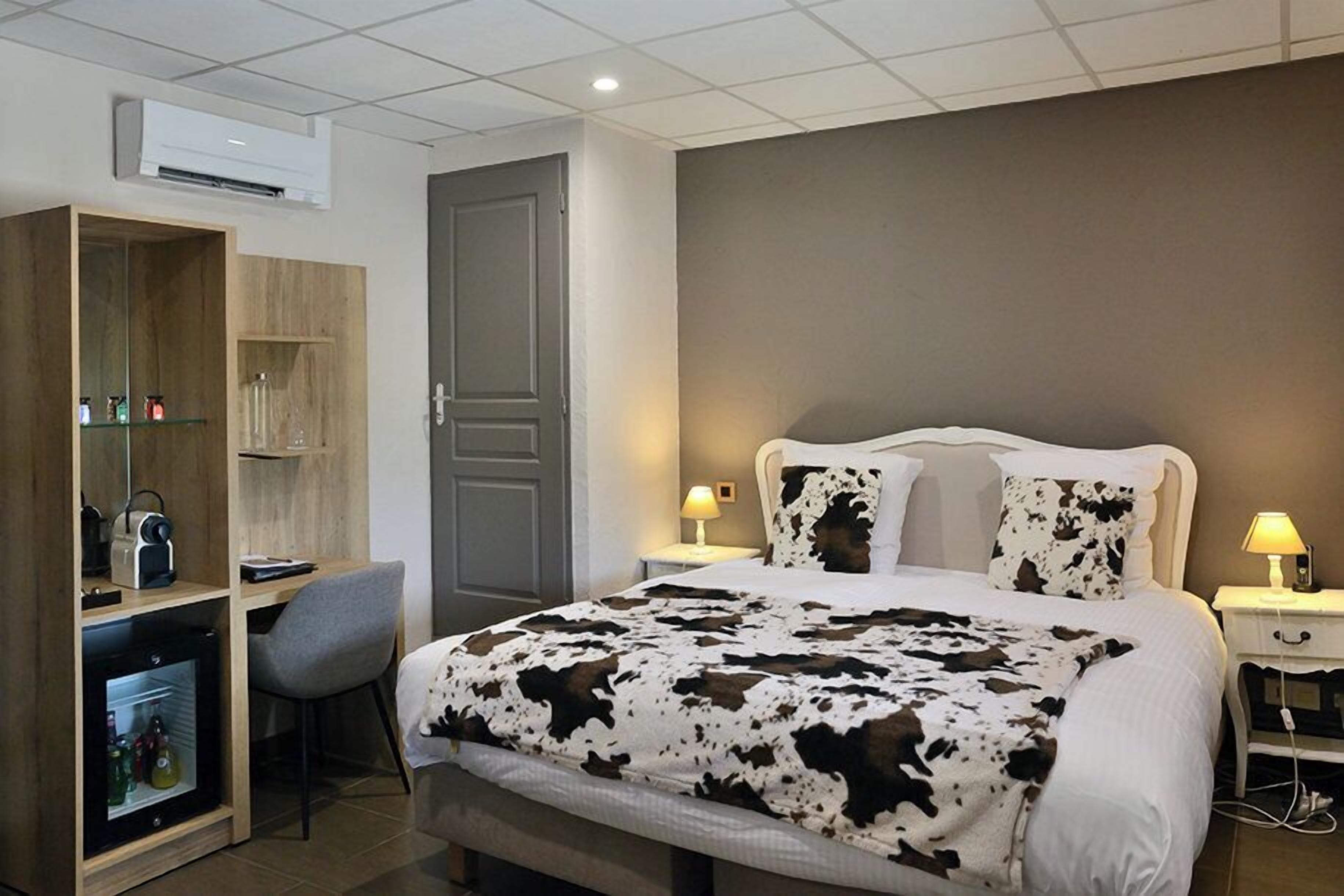 Habitación de hotel con cama, mesitas de noche, escritorio con silla, armario y equipo de aire acondicionado.