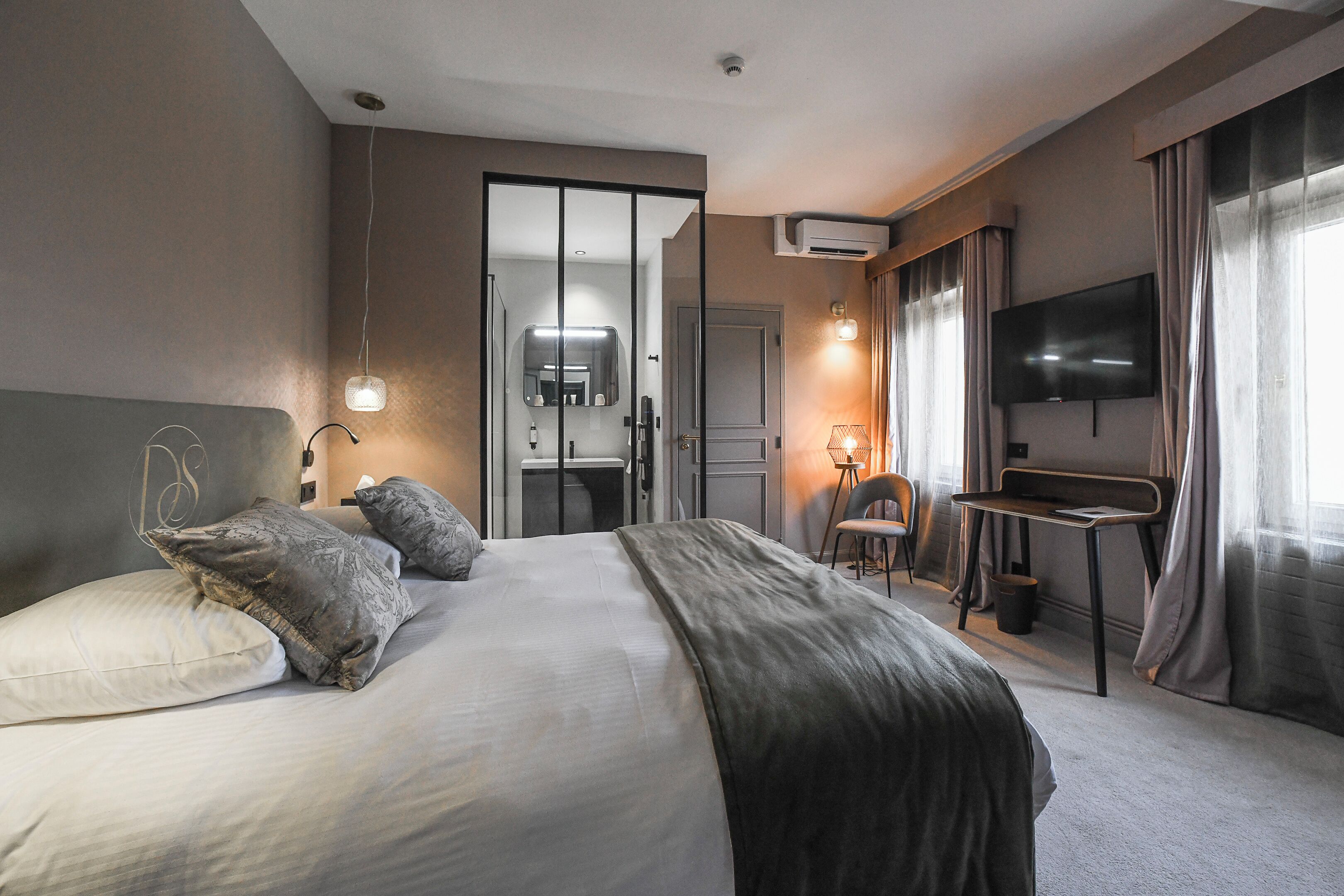 A hotel room with a bed, bedside table, TV, and a view of the bathroom.