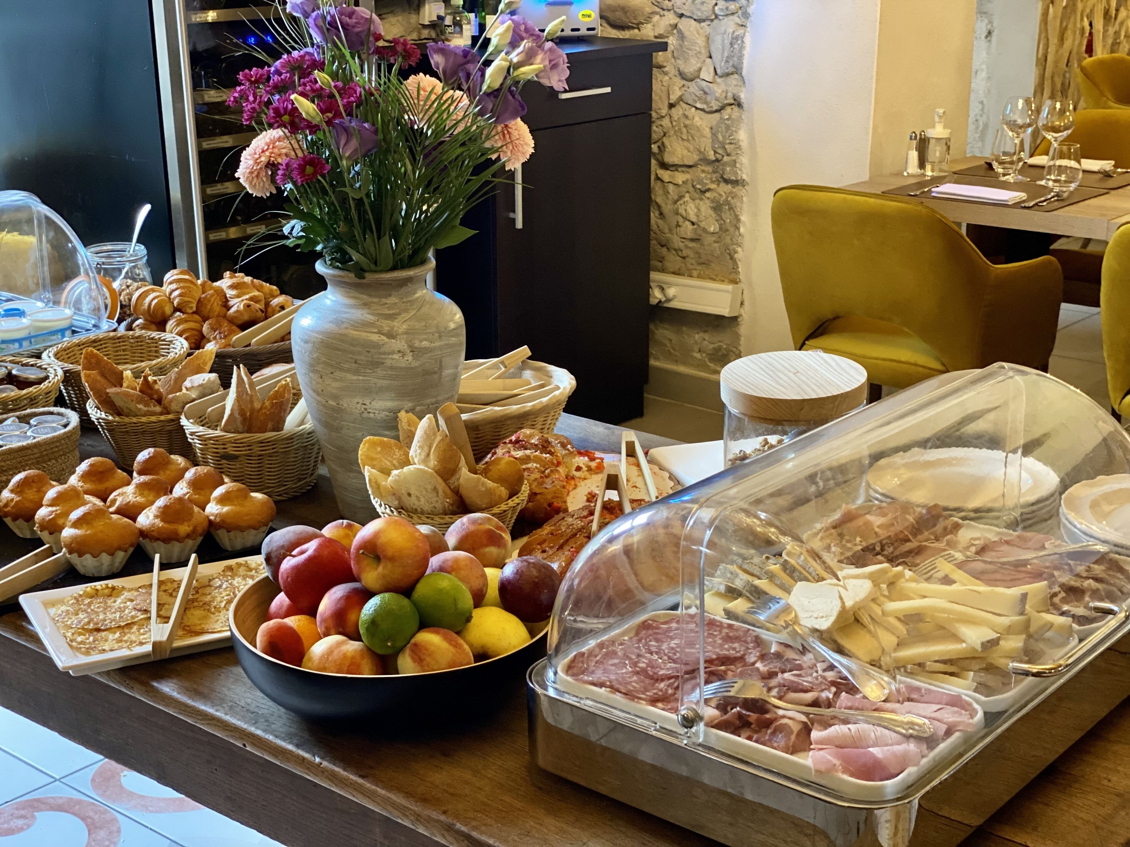 A buffet with various food items including fruits, pastries, and meats.