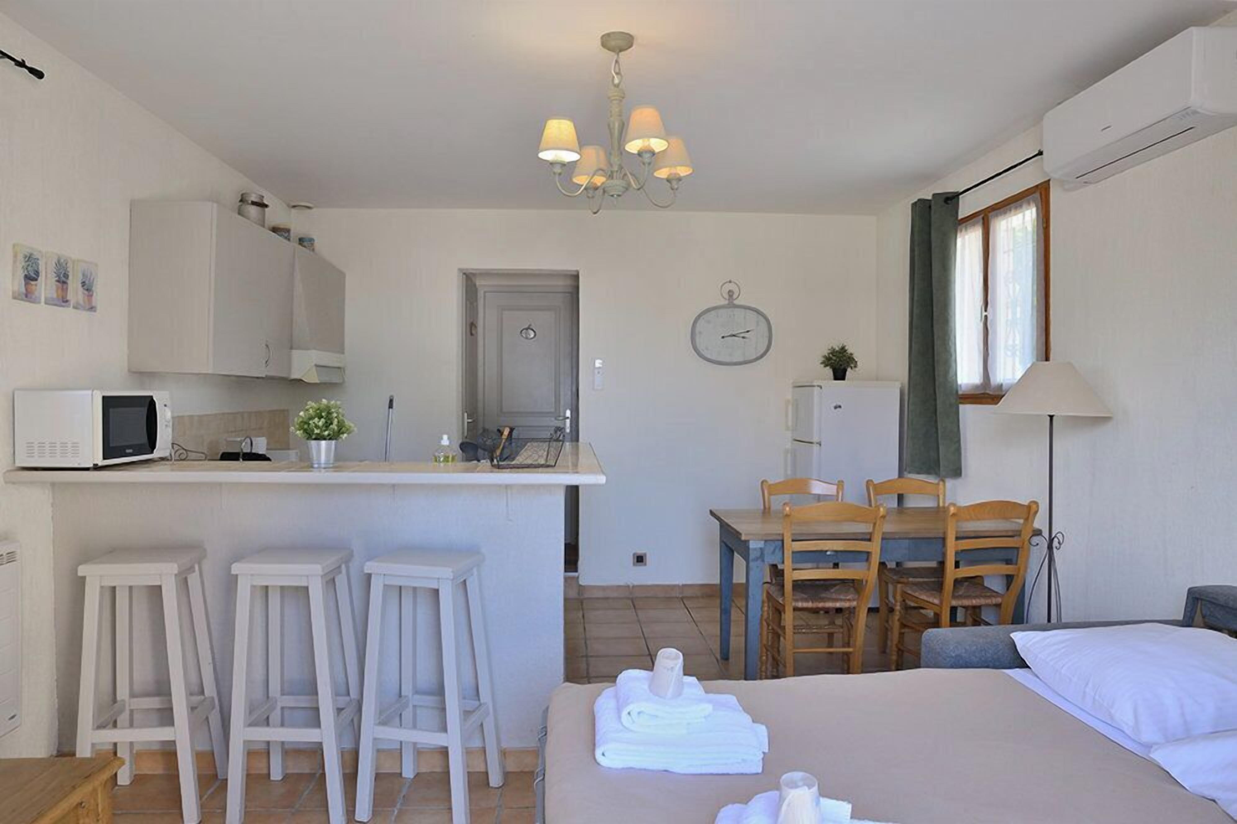 Una habitación de hotel compacta con kitchenette, comedor y cama.