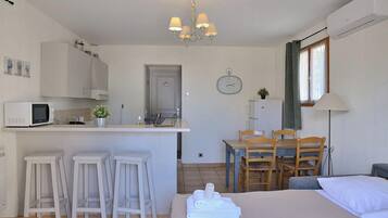 Una habitación de hotel compacta con kitchenette, comedor y cama.